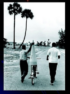 Scientists transporting rocket parts on a bicycle